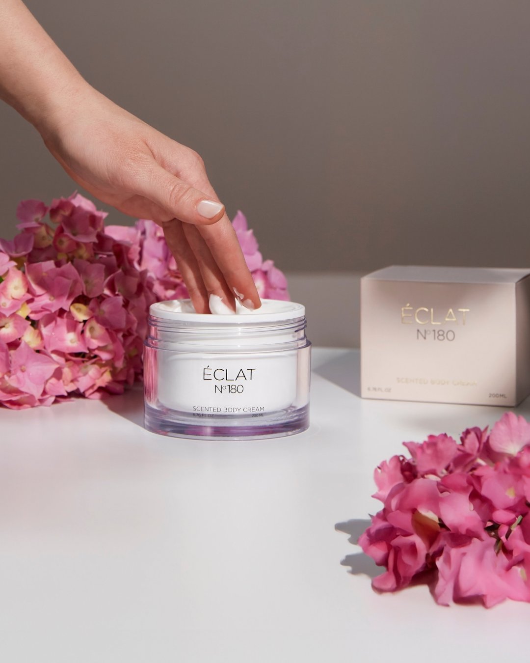 ÉCLAT 180 scented body cream from the Summer Collection 2025 – luxurious skincare for women, photographed in soft summer light surrounded by flowers..