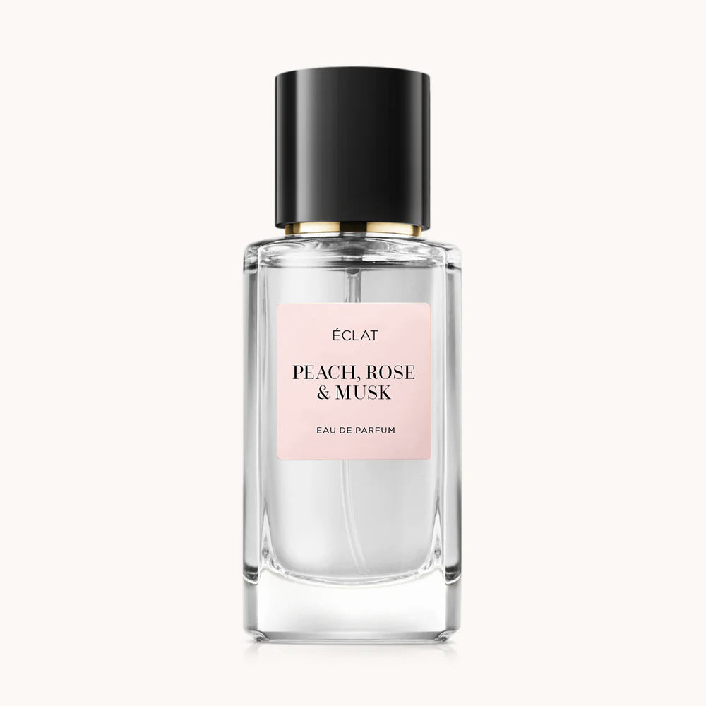 Flacon of the women’s perfume dupe ÉCLAT Peach, Rose & Musk, an elegant transparent glass bottle with a black cylindrical magnetic cap and a light pink label. The label displays the brand name ÉCLAT, the name Peach, Rose & Musk, and the phrase “Eau de Parfum”.