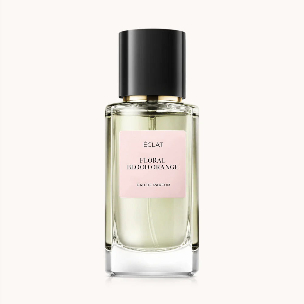 Flacon of the women’s perfume dupe ÉCLAT Floral Blood Orange, an elegant transparent glass bottle with a black cylindrical magnetic cap and a light pink label. The label displays the brand name ÉCLAT, the name Floral Blood Orange, and the phrase “Eau de Parfum”.