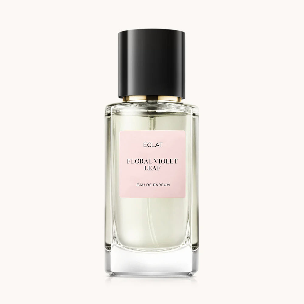 Flacon of the women’s perfume dupe ÉCLAT Floral Violet Leaf, an elegant transparent glass bottle with a black cylindrical magnetic cap and a light pink label. The label displays the brand name ÉCLAT, the name Floral Violet Leaf, and the phrase “Eau de Parfum”.