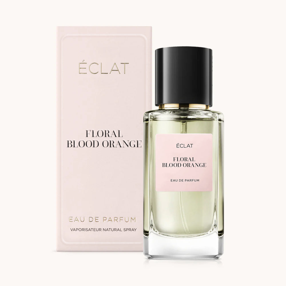 Fasetowana szklana butelka ÉCLAT Floral Blood Orange z czarną nakrętką obok bladoróżowego pudełka.