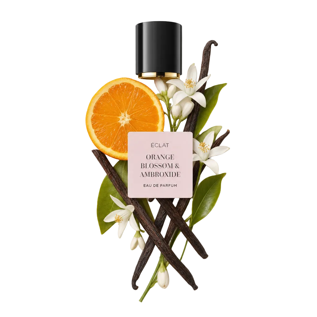 Harmonijna aranżacja laski wanilii, plasterków pomarańczy i kwiatów pomarańczy z bujnymi zielonymi liśćmi pod czarną nasadką z etykietą ÉCLAT Orange Blossom & Ambroxide.
