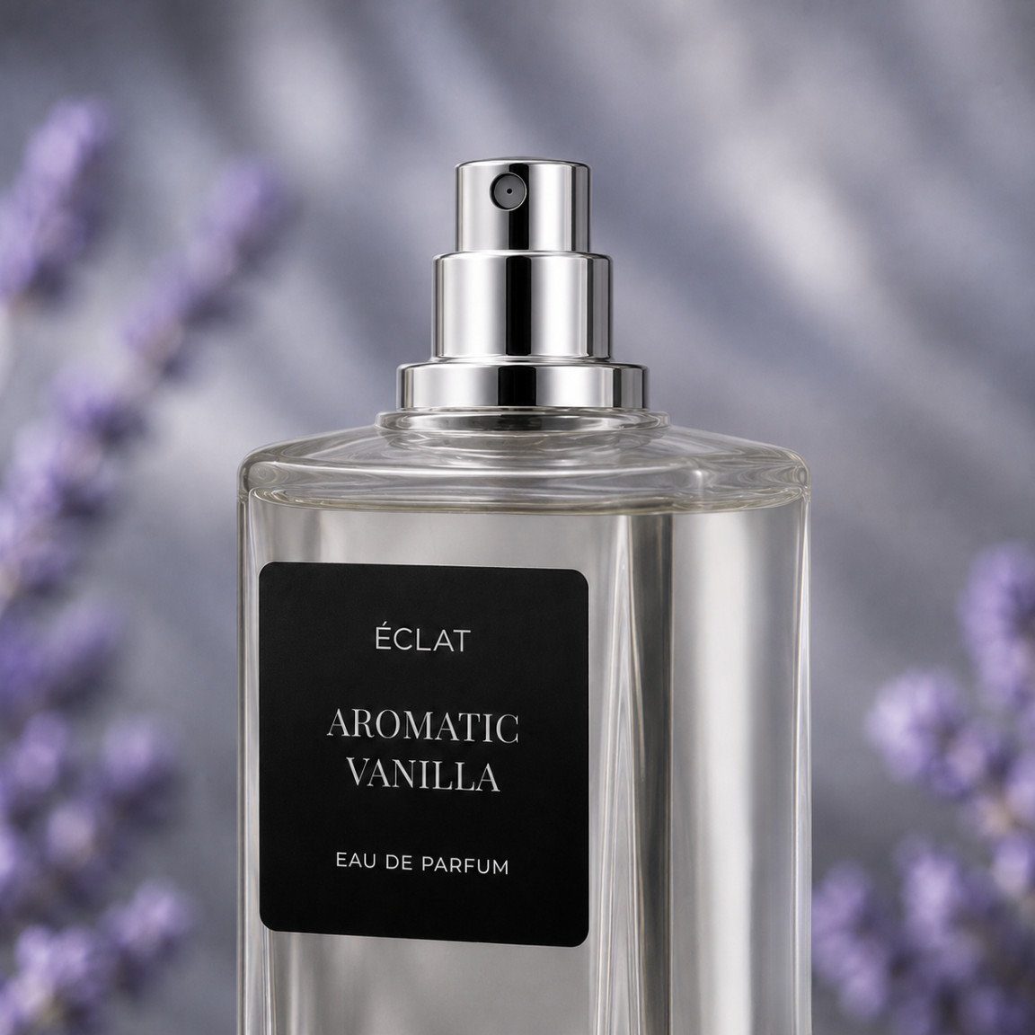 Przezroczysta szklana butelka ÉCLAT Aromatic Vanilla z polerowaną srebrną nakrętką i czarną matową etykietą, na tle rozmytych lawend.