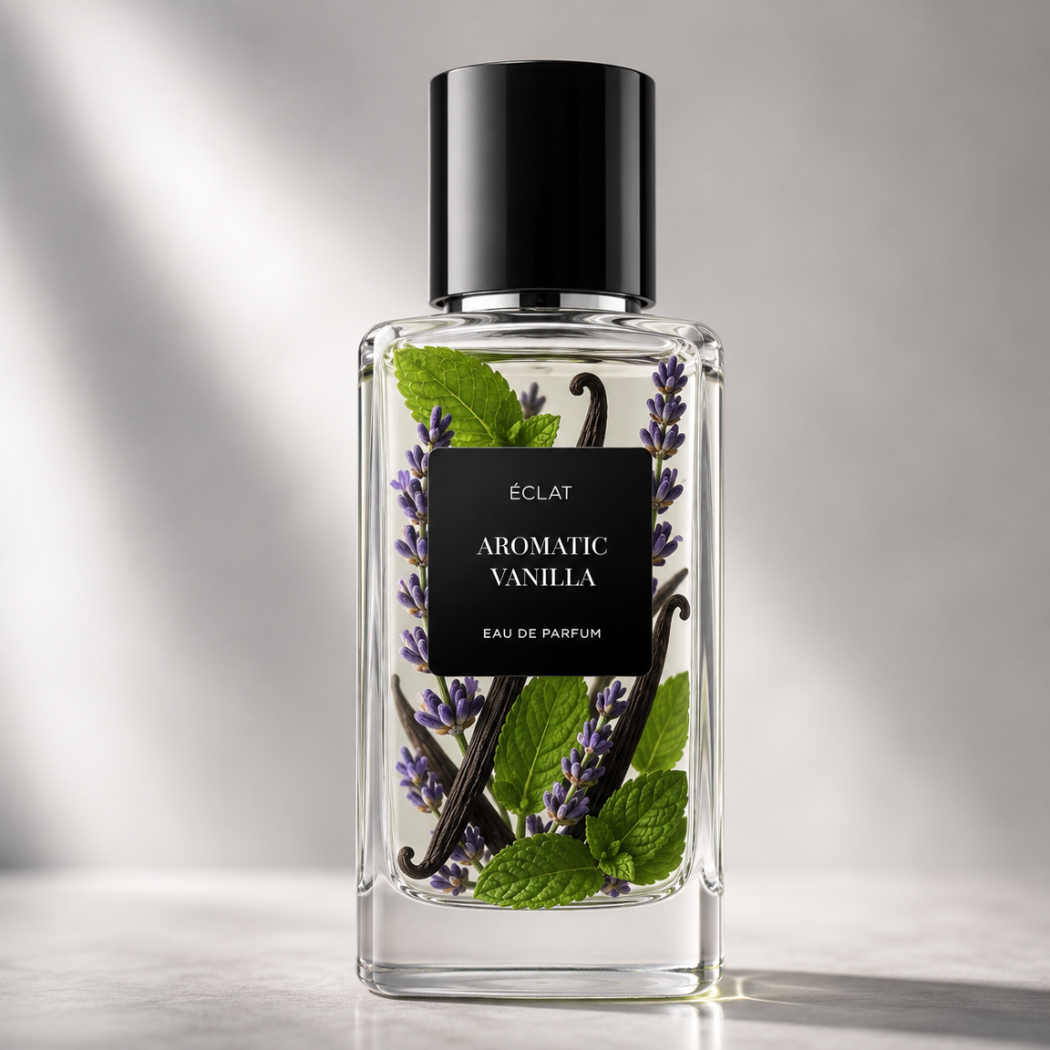 Elegancka szklana butelka ÉCLAT Aromatic Vanilla z czarną etykietą, gałązkami lawendy, strąkami wanilii i liśćmi mięty w środku.