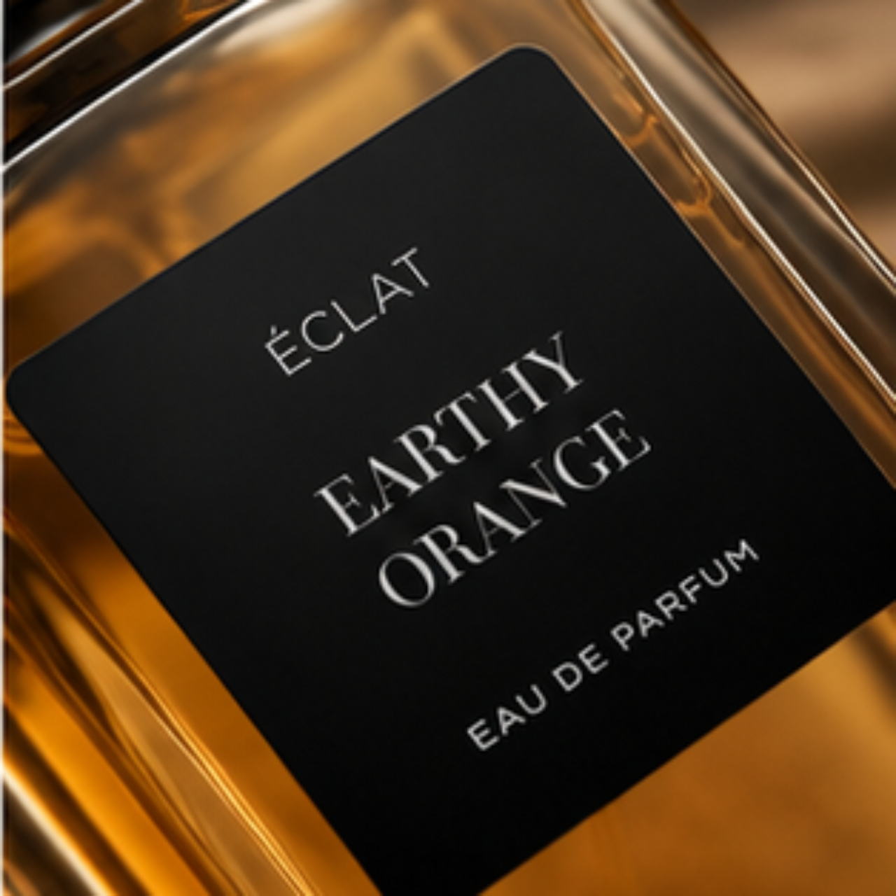 Szklany flakon o ciepłym bursztynowym odcieniu z czarną matową etykietą z napisem ÉCLAT Earthy Orange.