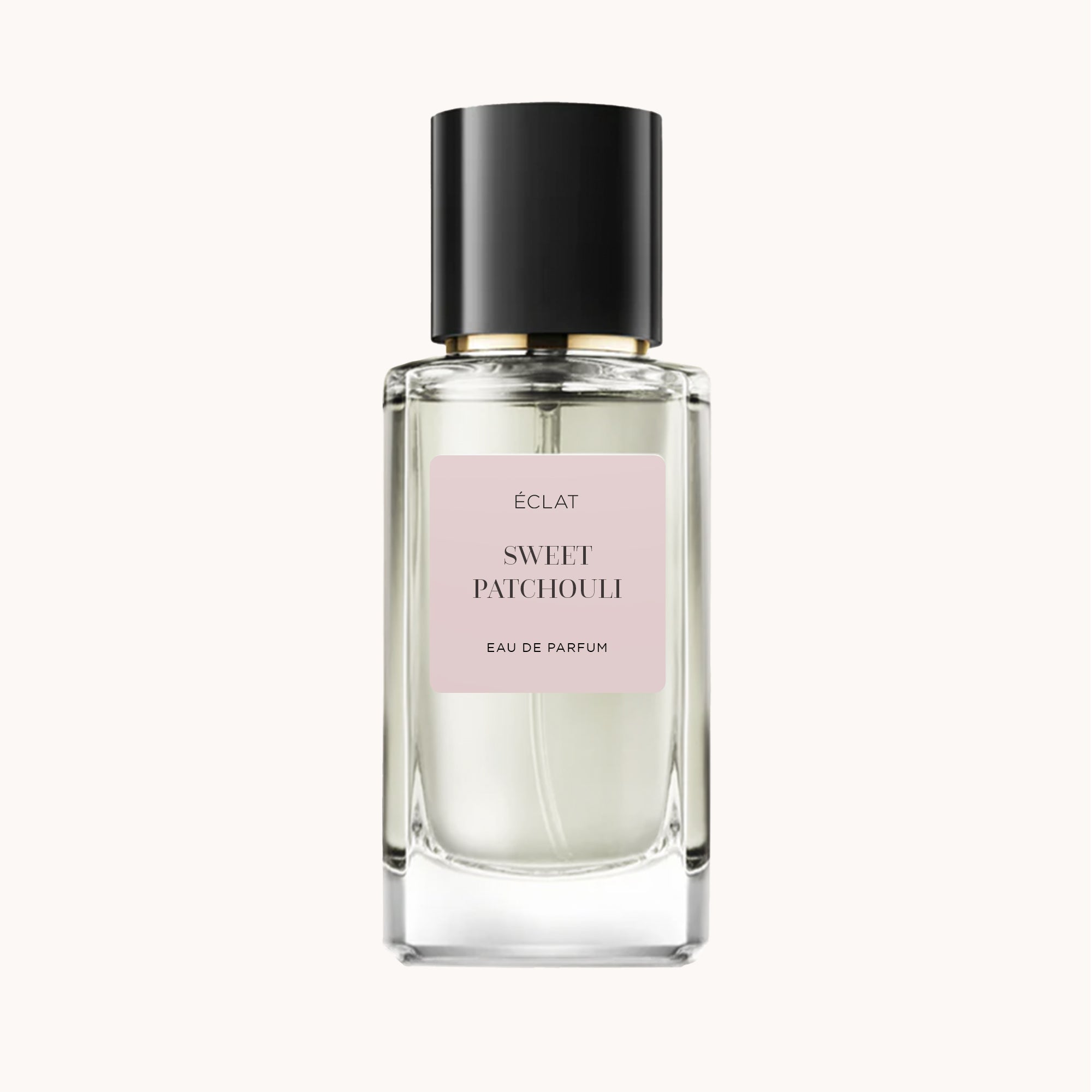 Fasetowana szklana butelka ÉCLAT Sweet Patchouli z czarną zakrętką i miękką różową etykietą.