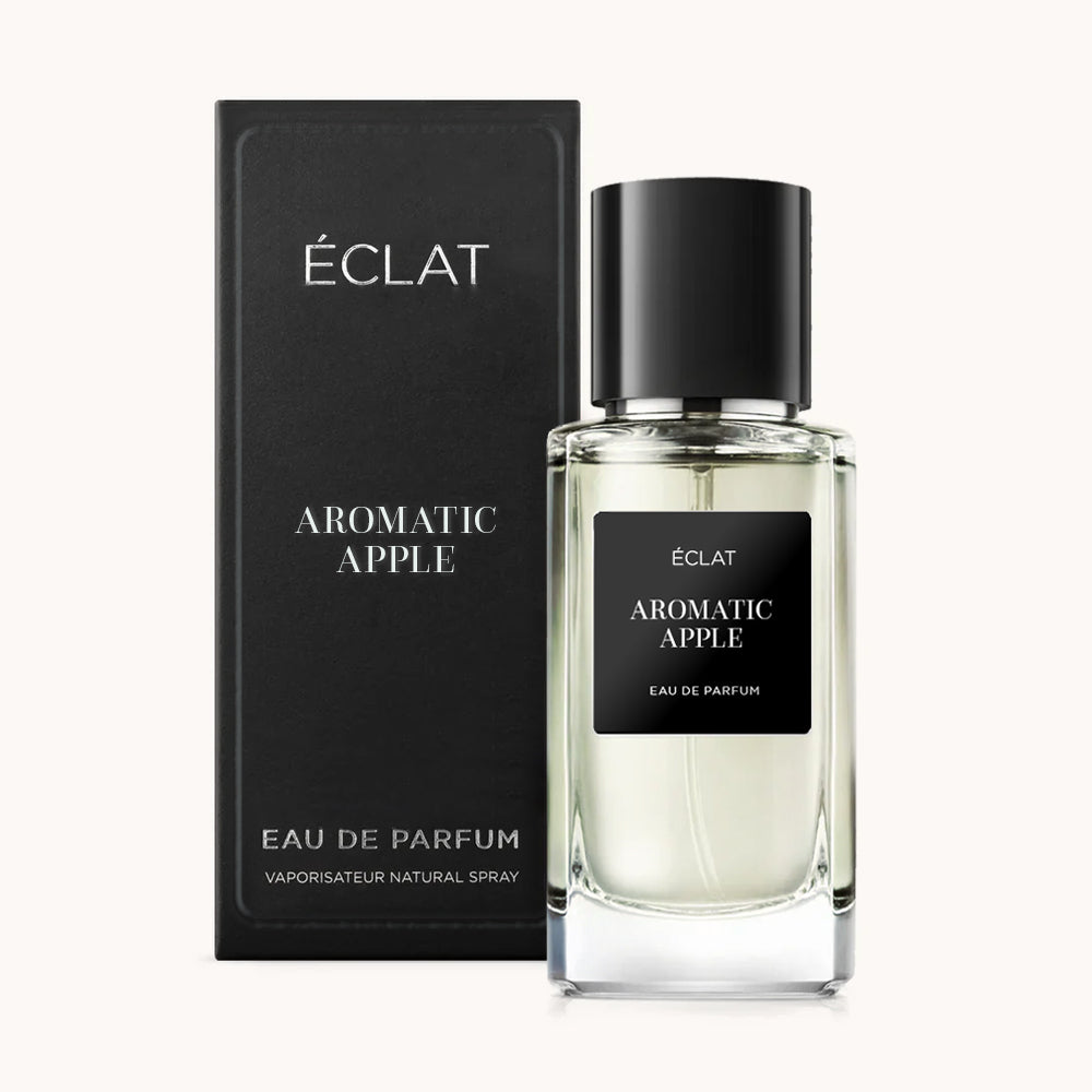 Przezroczysta szklana butelka ÉCLAT Aromatic Apple z czarną etykietą i korkiem, w towarzystwie eleganckiego czarnego pudełka.