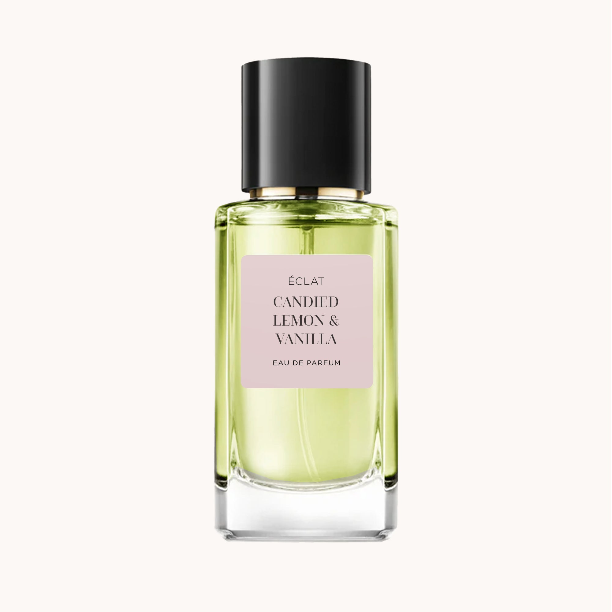 Fasetonowany flakon ÉCLAT Candied Lemon & Vanilla z bladym różowym etykietą i elegancką czarną nakrętką.