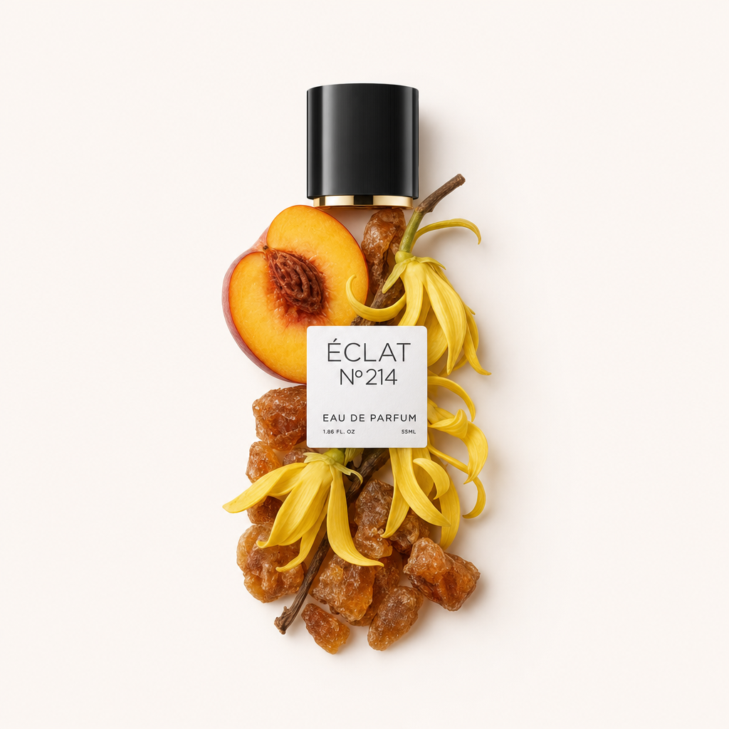 Kompozycja z żółtych kwiatów ylang-ylang, żywicy bursztynowej i pół brzoskwini otaczają czarną nakrętkę z etykietą ÉCLAT Creamy Amber.