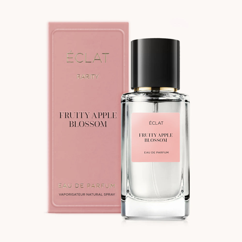 Fasetowany szklany flakon z różową etykietą i czarną zakrętką, obok pasującego różowego pudełka, prezentuje ÉCLAT Fruity Apple Blossom.
