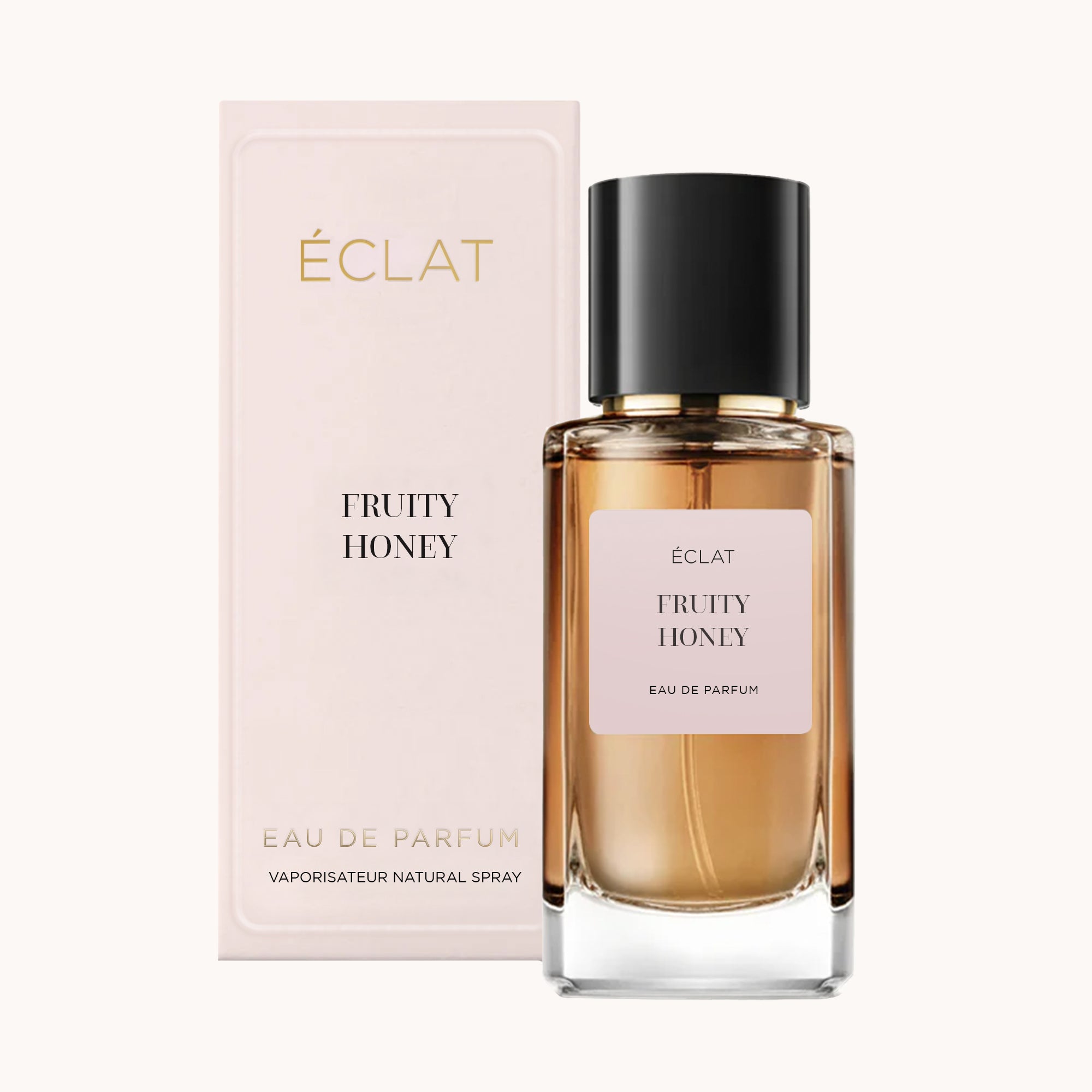 Fasetowany szklany flakon ÉCLAT Fruity Honey z czarną nakrętką, ustawiony przed różowym pudełkiem.