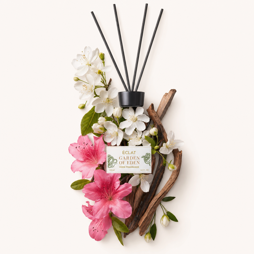 Kompozycja z białych i różowych kwiatów z gałązkami, z czarną zakrętką oznakowaną ÉCLAT Garden of Eden Room Fragrance Sticks.