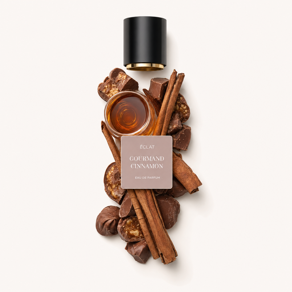 Starannie ułożona martwa natura ÉCLAT Gourmand Cinnamon przedstawia laski cynamonu, kawałki czekolady i orzechy wokół małej szklanej miseczki z płynem. Kompozycja jest zwieńczona czarną nakrętką z etykietą.