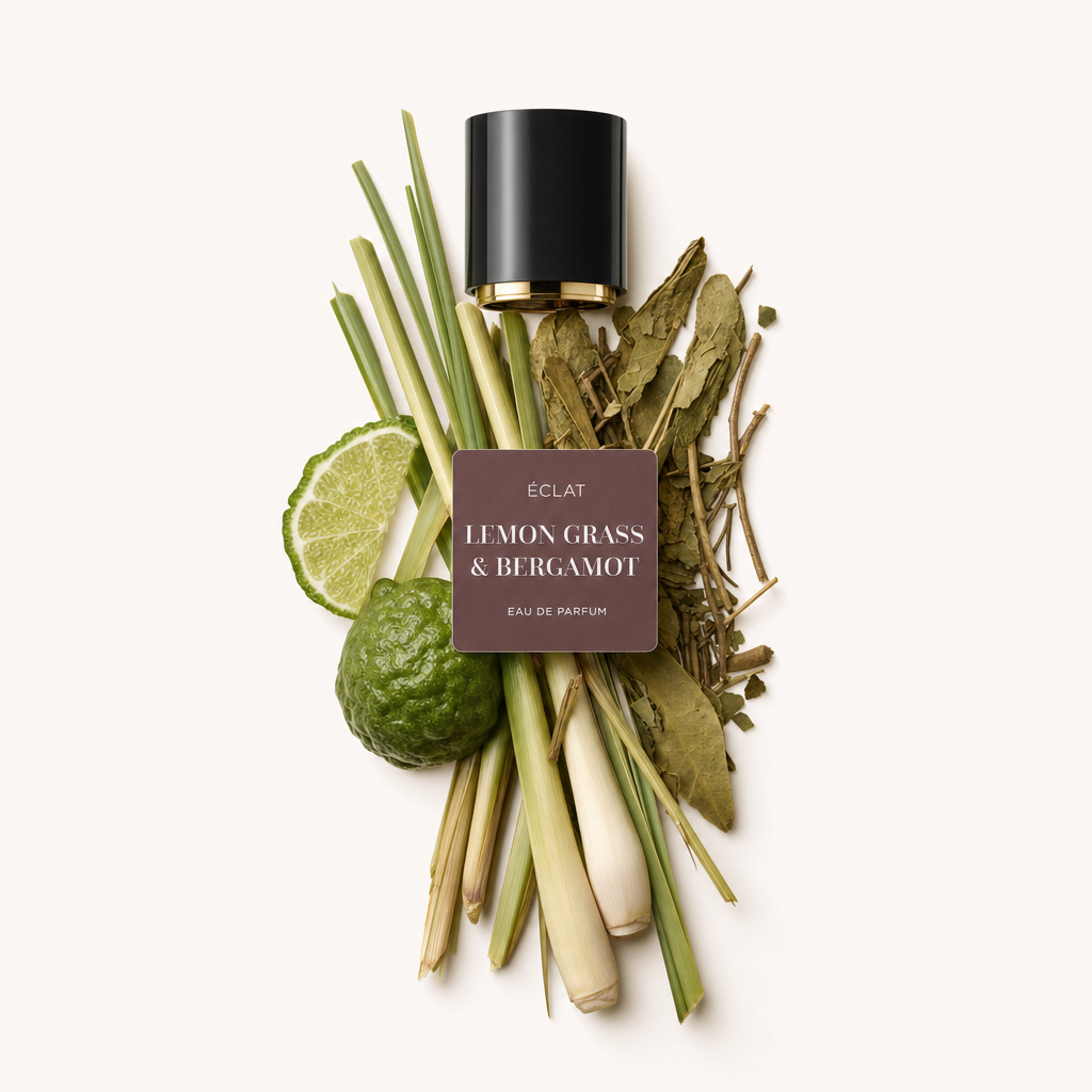 Aranżacja z łodygi trawy cytrynowej, liści kaffir lime, plasterków limonki i całego owocu bergamotki, obok czarnej nakrętki z etykietą ÉCLAT Lemon Grass & Bergamot.