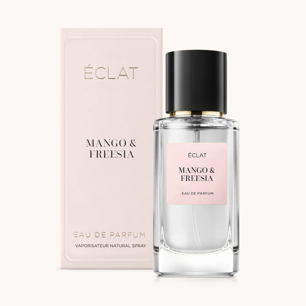 Perfumy ÉCLAT Mango & Freesia w przezroczystym szklanym flakonie z czarną nakrętką, z towarzyszącym jasnoróżowym pudełkiem.