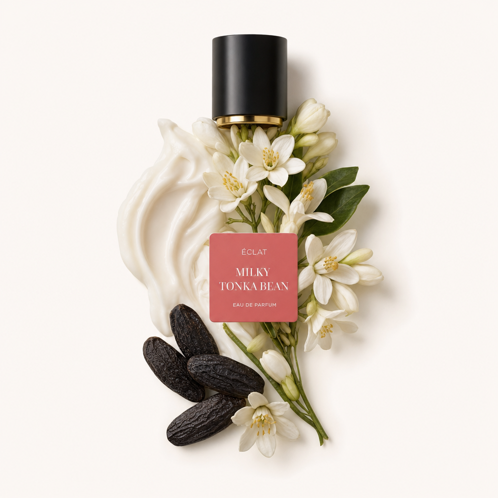 Kompozycja z kremowych zawijasów, fasoli tonka i delikatnych białych kwiatów, z czarną nakrętką z etykietą ÉCLAT Milky Tonka Bean.