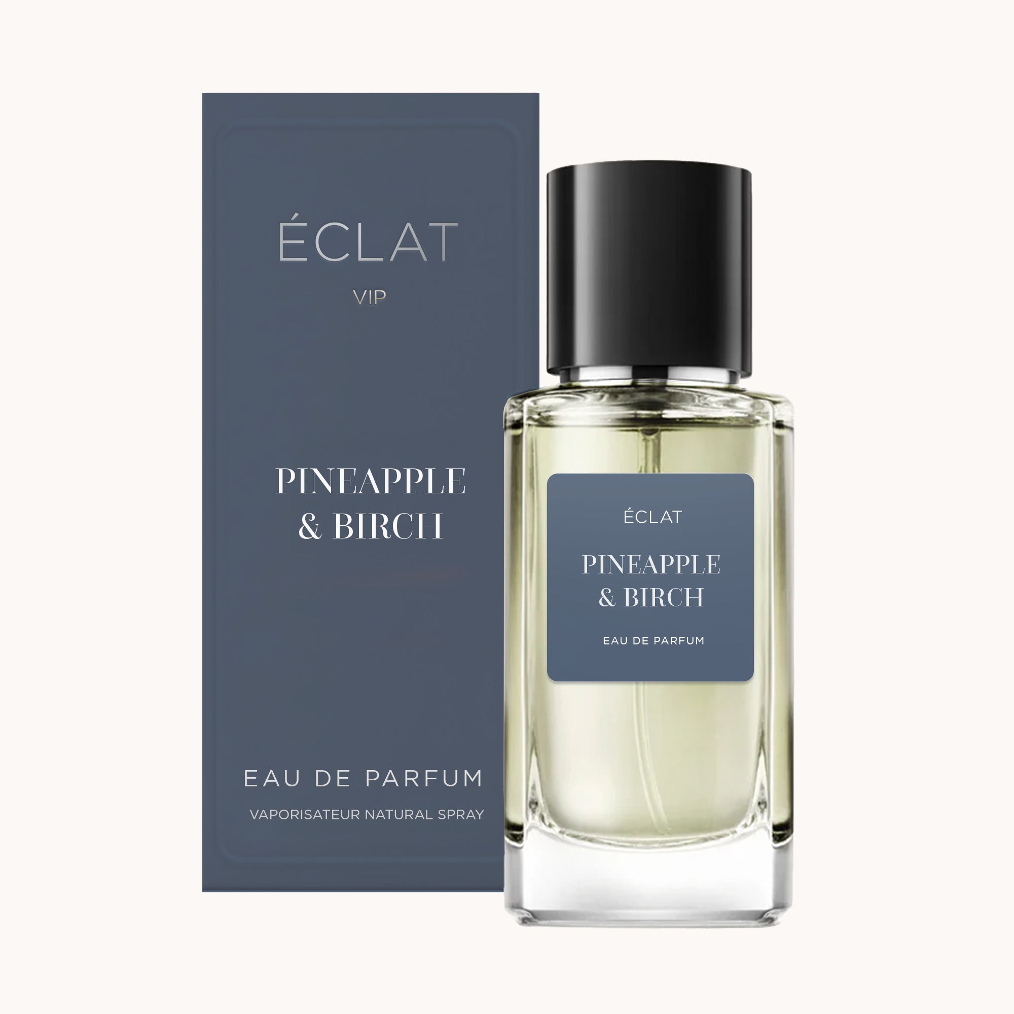 Perfumy ÉCLAT Pineapple & Birch w przezroczystej szklanej butelce z czarnym korkiem, obok pasującego ciemnoniebieskiego pudełka.