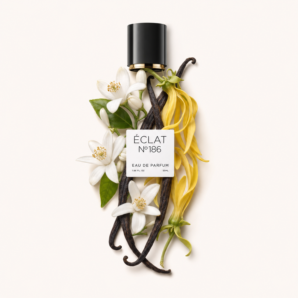 Aranżacja białych kwiatów pomarańczy i żółtych płatków ylang-ylang, z akcentem ciemnych lasek wanilii, otacza czarną nakrętkę z etykietą ÉCLAT Powdery Orange Blossom.