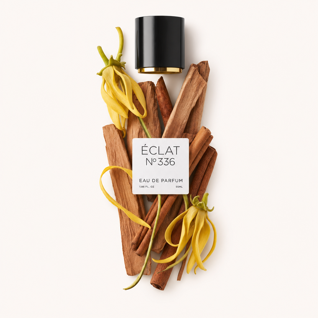 Aranżacja żółtych kwiatów ylang-ylang i patyczków sandałowych towarzyszy czarnej nakrętce z etykietą ÉCLAT Powdery Sandalwood.