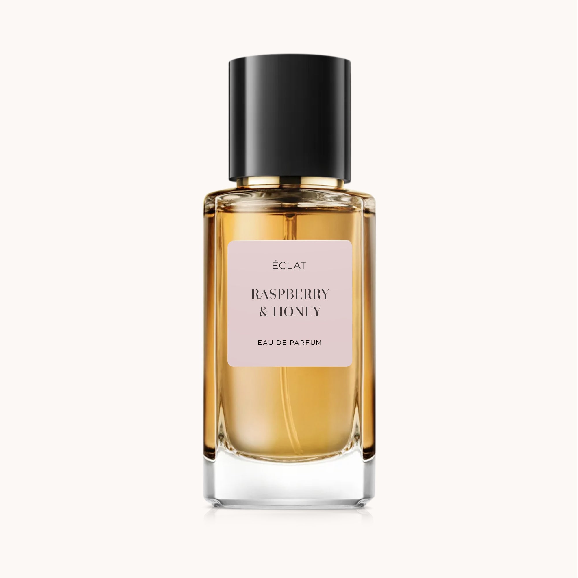 Facetowana szklana butelka perfum ÉCLAT Raspberry & Honey z matową etykietą i czarną nakrętką.