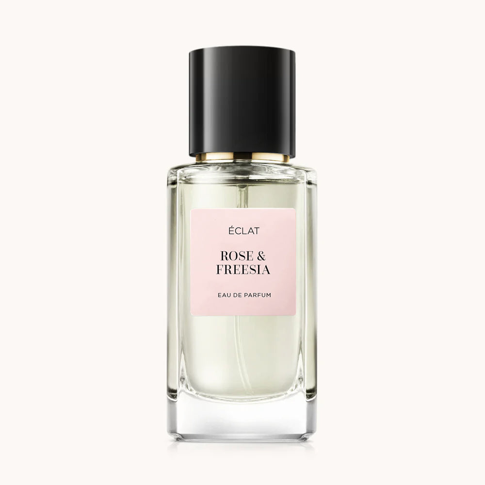 Fasetowana szklana butelka z etykietą ÉCLAT Rose & Freesia, czarną nakrętką i miękką różową etykietą.