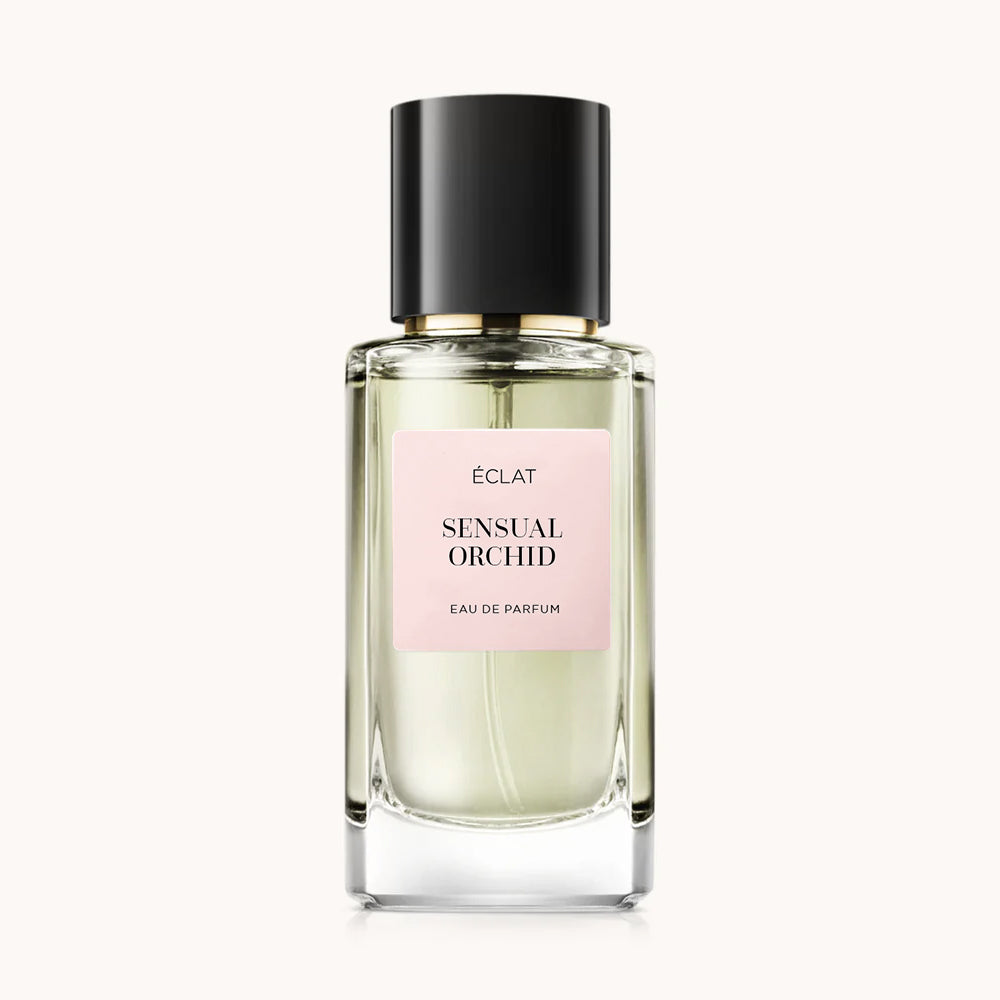 Perfumy ÉCLAT Sensual Orchid w przezroczystej, fasetowanej szklanej butelce z czarną nakrętką i delikatnoróżową etykietą.