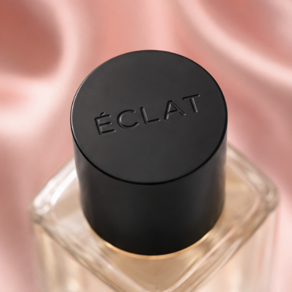 ÉCLAT Silk & Cashmere w fasetowanej szklanej butelce z matową czarną nakrętką na różowym satynowym tle.