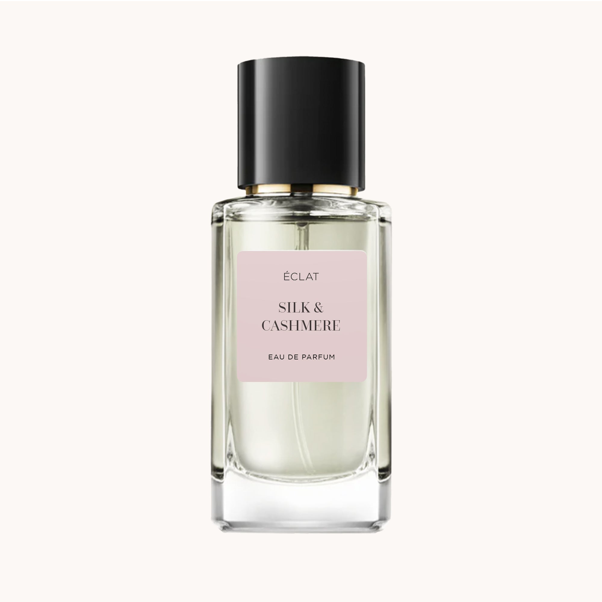 Fasetowana szklana butelka z matową czarną zakrętką i jasnoróżową etykietą z napisem ÉCLAT Silk & Cashmere.
