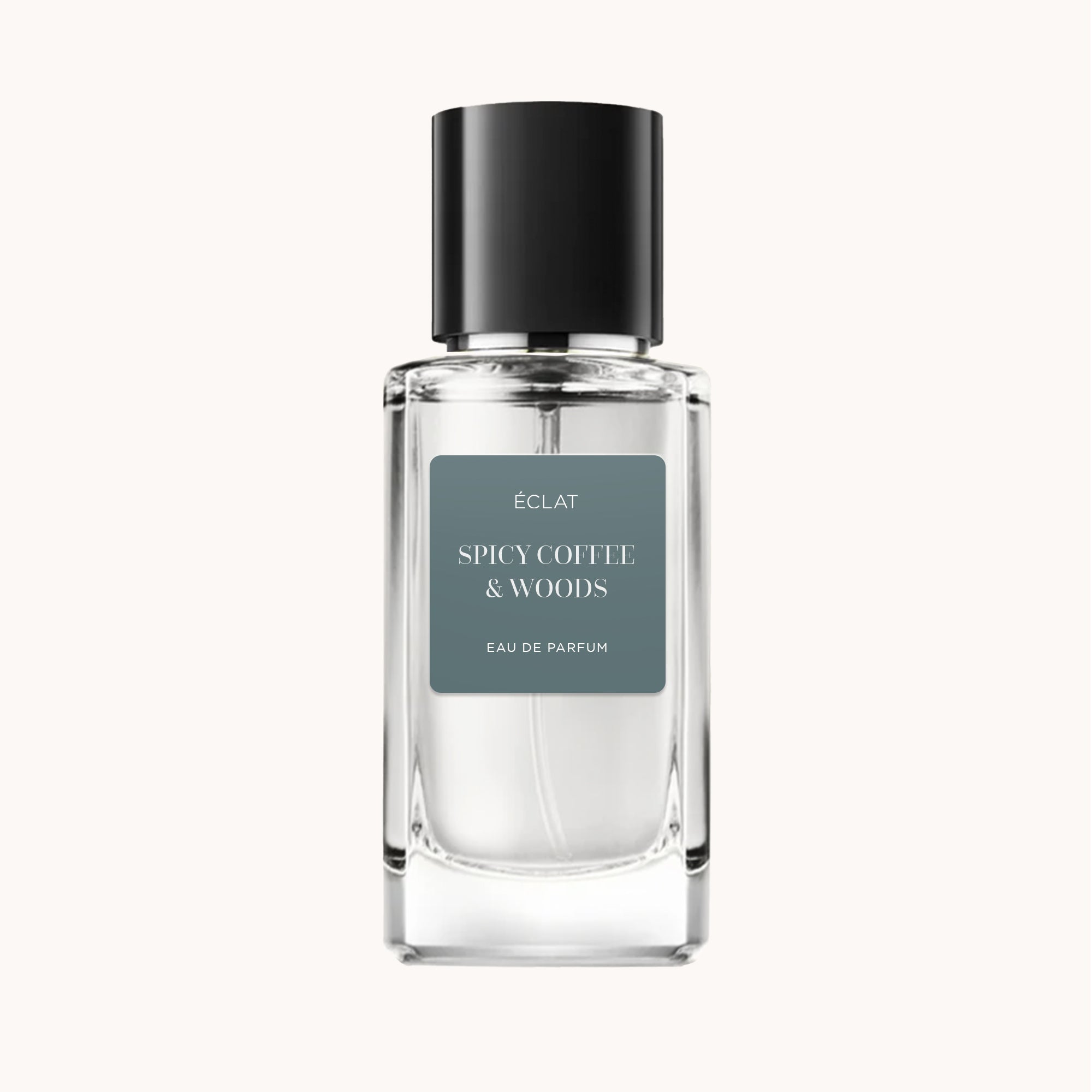 Butelka perfum ÉCLAT Spicy Coffee & Woods ma przezroczyste fasetowane szkło z czarną nakrętką i matową szarą etykietą.