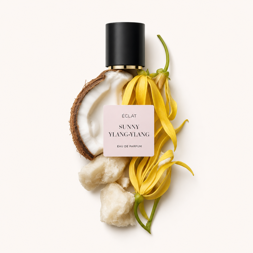 Aranżacja świeżych kwiatów ylang-ylang, połowa kokosa i kawałki masła shea, z czarną nakrętką z etykietą ÉCLAT Sunny Ylang-Ylang.