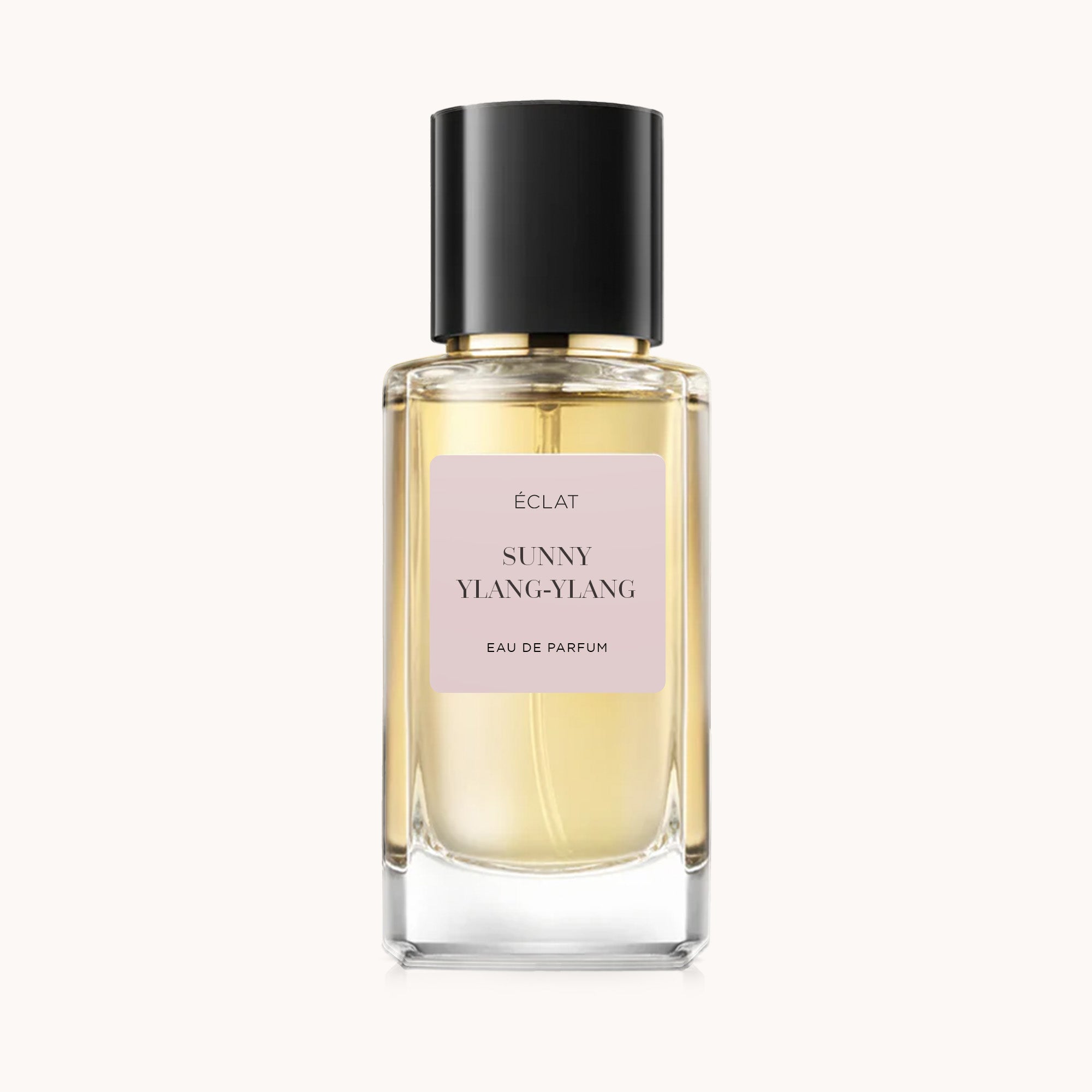 Fasetowana szklana butelka ÉCLAT Sunny Ylang-Ylang z beżową etykietą i czarną błyszczącą zakrętką.
