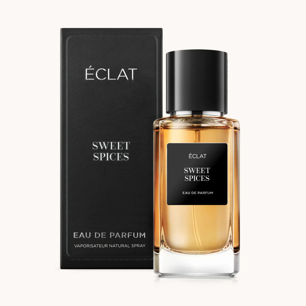 Zapach ÉCLAT Sweet Spices w eleganckiej szklanej butelce z czarną nakrętką i etykietą, w towarzystwie pasującego czarnego pudełka.