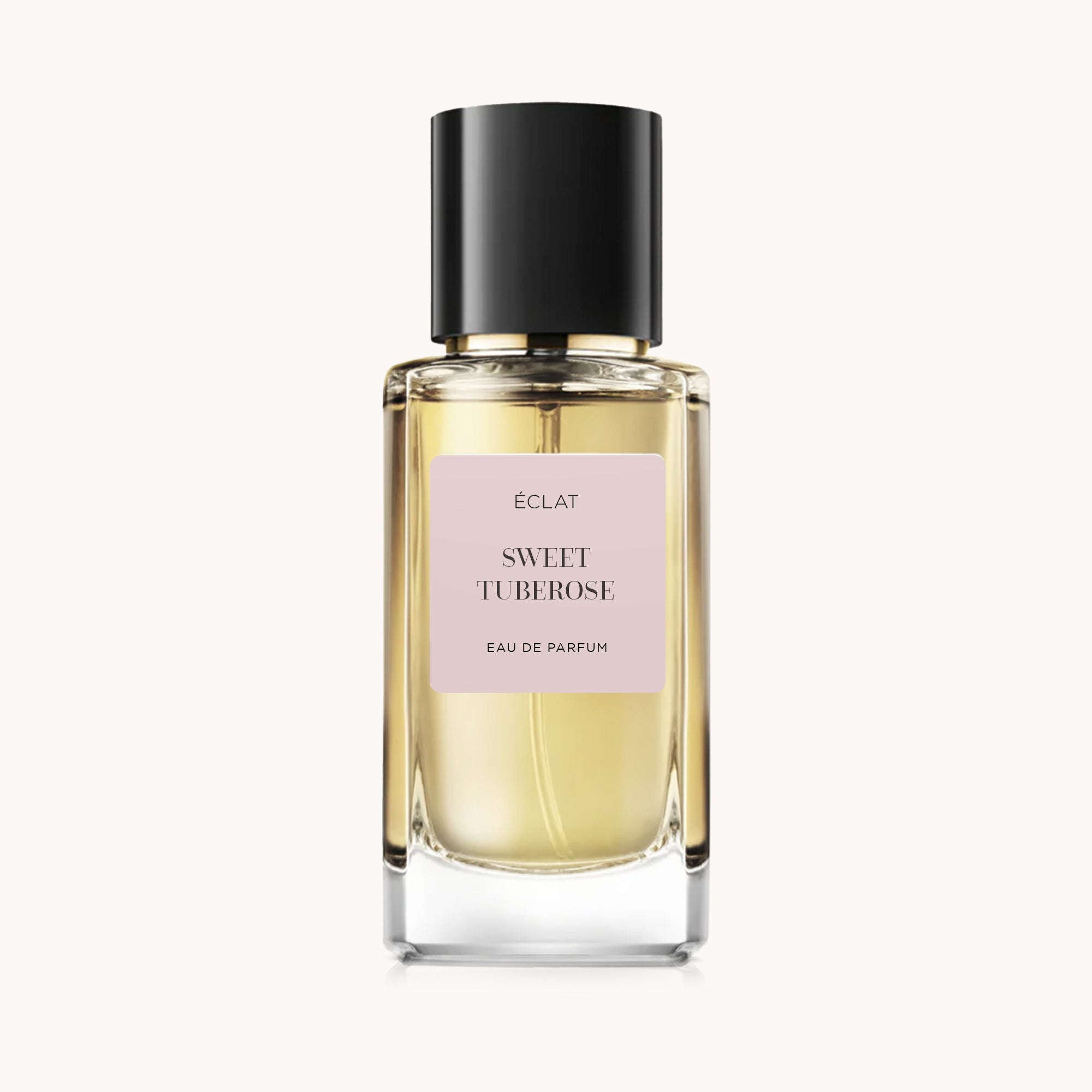 Perfumy ÉCLAT Sweet Tuberose w szklanej butelce z czarną nakrętką i różową etykietą.
