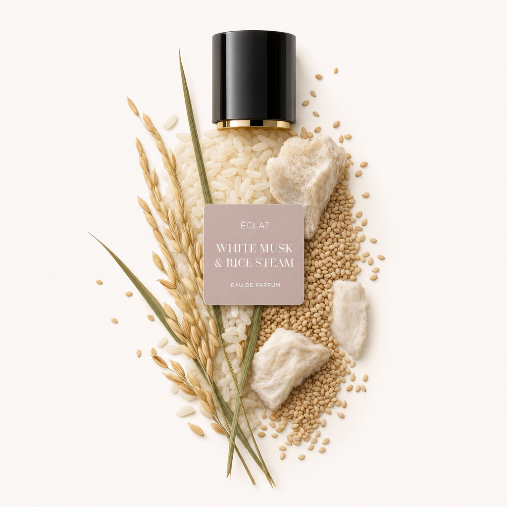 Artystyczna kompozycja ziaren ryżu, puszystych kawałków piżma i zbóż otacza czarną zakrętkę z etykietą ÉCLAT White Musk & Rice Steam.